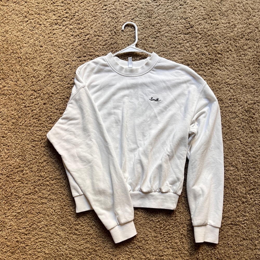White crew neck with smile embroidered on the leftside
